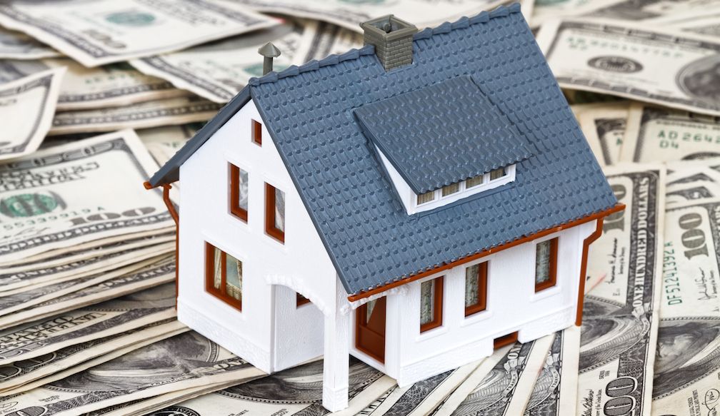 Model house sitting on a pile of cash
