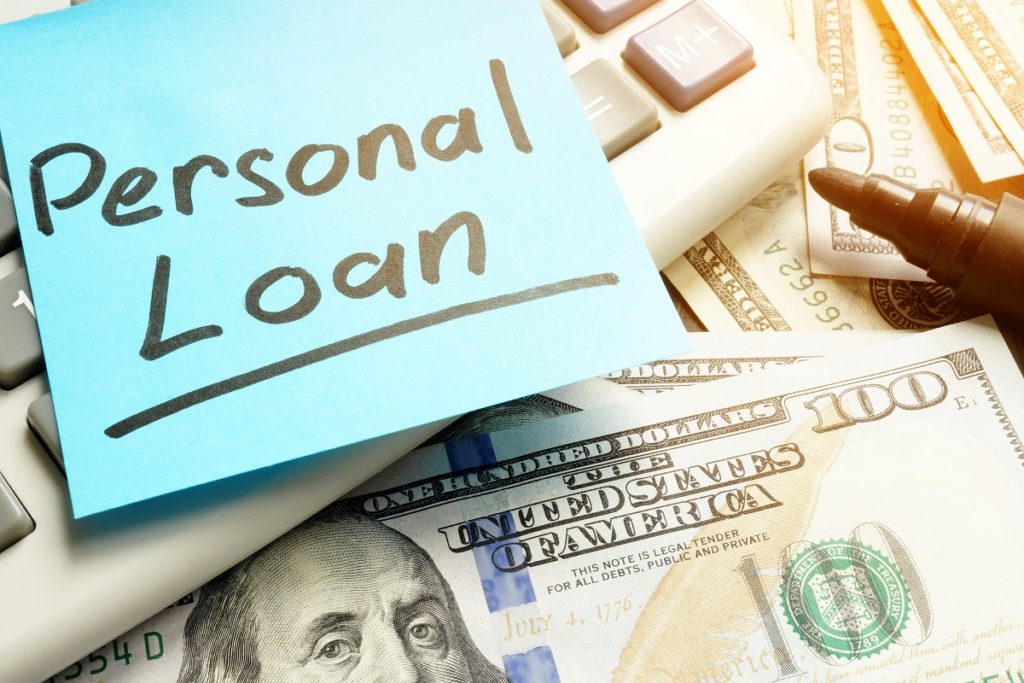 A note reading Personal Loan on top of cash and a calculator